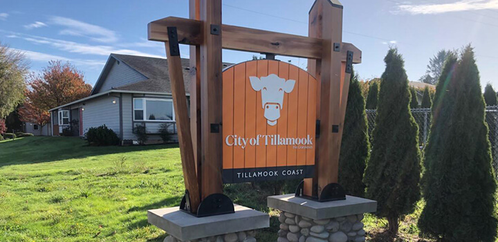 Bright orange sign with a white cow on it that reads "City of Tillamook"